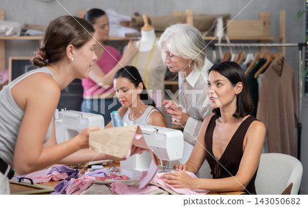In sewing class young woman working on machine and discussing pattern In sewing class young woman working on machine and discussing pattern 143050682