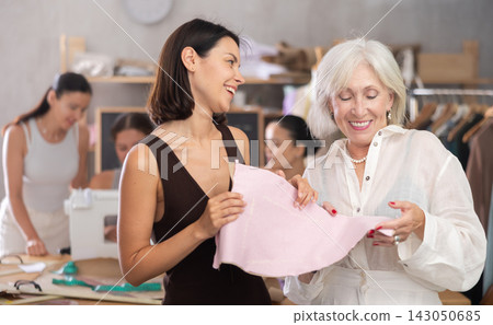 Young and elderly women discussing pattern at sewing master class 143050685
