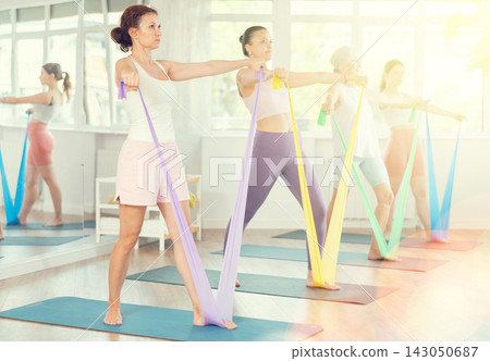 Women are doing stretching exercise with resistance bands in gym. Teamwork, good mood and healthy lifestyle concept 143050687