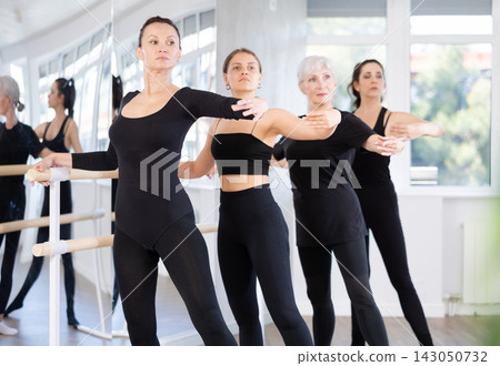 Woman performing battement tendu at barre in ballet studio Woman performing battement tendu at barre in ballet studio 143050732