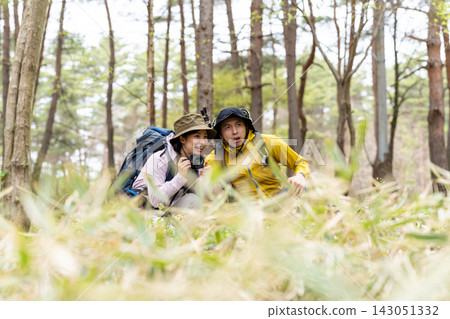 一男一女在森林裡健行,手裡拿著相機。 一男一女在森林裡健行,手裡拿著相機。 143051332