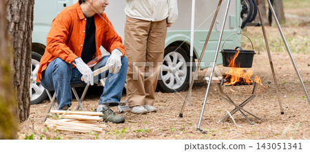 A man and a woman chatting around a campfire at a campsite. A man and a woman chatting around a campfire at a campsite. 143051341
