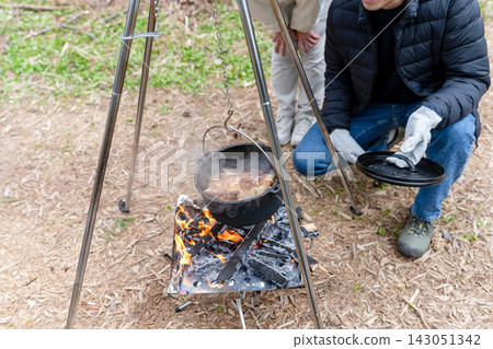 一男一女在露營地用荷蘭烤爐煮飯。 一男一女在露營地用荷蘭烤爐煮飯。 143051342