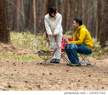 A scene of a man and woman enjoying an outdoor camping trip around a campfire. A scene of a man and woman enjoying an outdoor camping trip around a campfire. 143051345