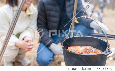 男男女女圍坐在露營地,用荷蘭烤爐煮飯。 男男女女圍坐在露營地,用荷蘭烤爐煮飯。 143051380
