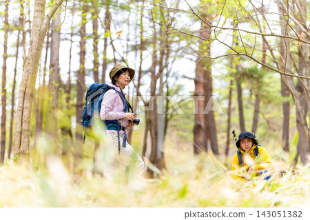 森林裡,一個女人拿著相機,一個男人在看她。 森林裡,一個女人拿著相機,一個男人在看她。 143051382