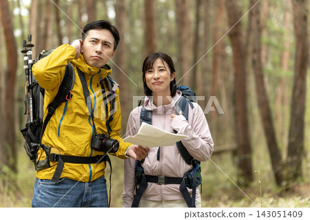 一對徒步旅行的情侶在森林裡看地圖。 一對徒步旅行的情侶在森林裡看地圖。 143051409