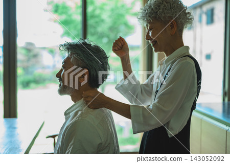 理髮師正在為顧客修剪白髮。 143052092
