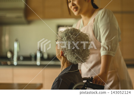 A caregiver assists an elderly person in a wheelchair. A caregiver assists an elderly person in a wheelchair. 143052124