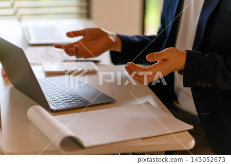 一位男士在參加線上會議時,正在辦公桌前工作。 一位男士在參加線上會議時,正在辦公桌前工作。 143052673