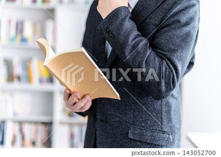 A man deep in thought while reading a book. A man deep in thought while reading a book. 143052700