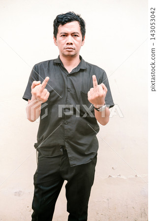 Man in black shirt showing middle fingers against a wall Man in black shirt showing middle fingers against a wall 143053042