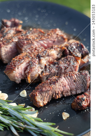 Sliced Grilled Beef Steak with Rosemary and Garlic on Black Plate Sliced Grilled Beef Steak with Rosemary and Garlic on Black Plate 143053183