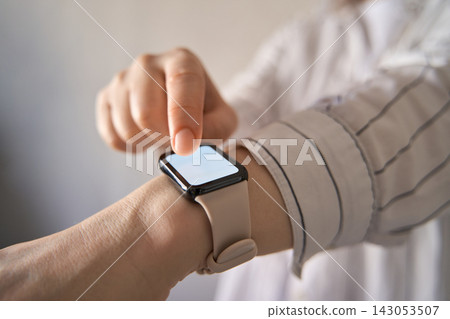 Person Tapping Smartwatch On Wrist Indoors In Closeup Profile View 143053507