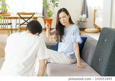 一位年輕的日本女子在客廳裡對著一位年輕的日本男子發火。 143053945