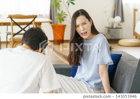 A young Japanese woman gets angry at a young Japanese man in the living room. A young Japanese woman gets angry at a young Japanese man in the living room. 143053946