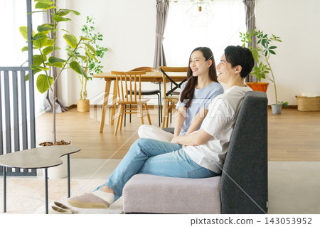 一對年輕的日本明星夫婦並排坐在客廳沙發上聊天。 一對年輕的日本明星夫婦並排坐在客廳沙發上聊天。 143053952
