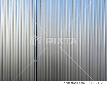 Vertical silver corrugated metal wall panel texture background with a vertical pipe fixture. 143054129