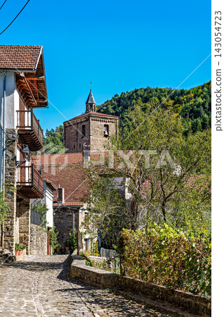 Strolling through Isaba in Roncal valley, Pyrenees, Navarre in Spain with brownish tiled roofs of residential buildings Strolling through Isaba in Roncal valley, Pyrenees, Navarre in Spain with brownish tiled roofs of residential buildings 143054723
