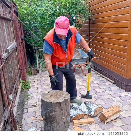 Man preparing firewood with an axe in a backyard Man preparing firewood with an axe in a backyard 143055223