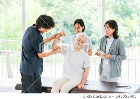 A senior woman receiving arm rehabilitation for shoulder and elbow pain. Functional training of the upper limbs by a physical therapist. A senior woman receiving arm rehabilitation for shoulder and elbow pain. Functional training of the upper limbs by a physical therapist. 143055405