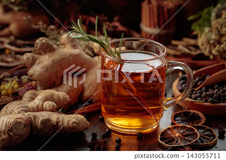 Warming herbal tea with fresh ginger, dried orange slices, juniper berries and spices served in a glass mug. Warming herbal tea with fresh ginger, dried orange slices, juniper berries and spices served in a glass mug. 143055711
