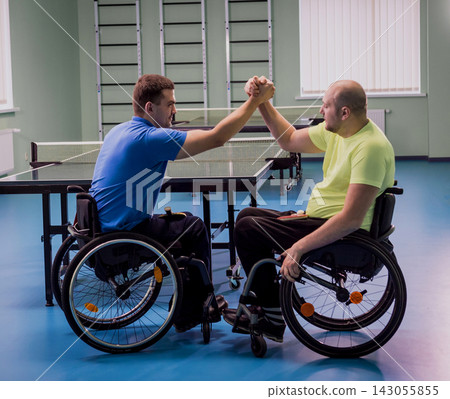 Disabled adult men shaking hands after playing table tennis Disabled adult men shaking hands after playing table tennis 143055855