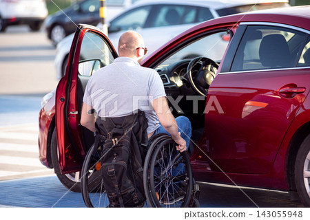 Young handicapped driver getting in red car fom wheelchair Young handicapped driver getting in red car fom wheelchair 143055948