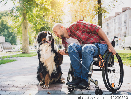 Happy young man with a physical disability in a wheelchair with his dog. Happy young man with a physical disability in a wheelchair with his dog. 143056290