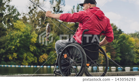 Person with a physical disability in a wheelchair fishing from fishing pier. Person with a physical disability in a wheelchair fishing from fishing pier. 143056293