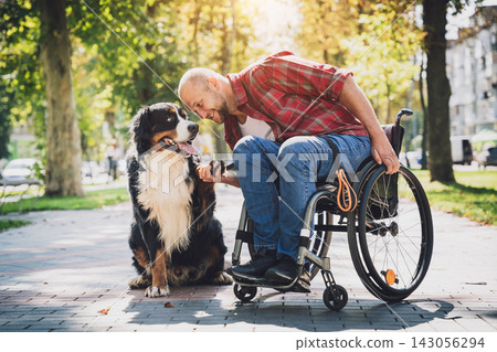 Happy young man with a physical disability in a wheelchair with his dog. 143056294