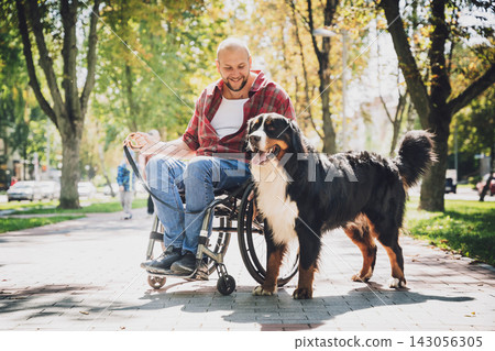 Happy young man with a physical disability in a wheelchair with his dog. Happy young man with a physical disability in a wheelchair with his dog. 143056305