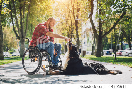 Happy young man with a physical disability in a wheelchair with his dog. Happy young man with a physical disability in a wheelchair with his dog. 143056311