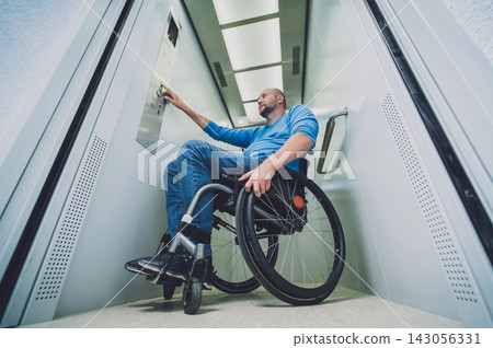 Person with a physical disability in a wheelchair using lift in building Person with a physical disability in a wheelchair using lift in building 143056331