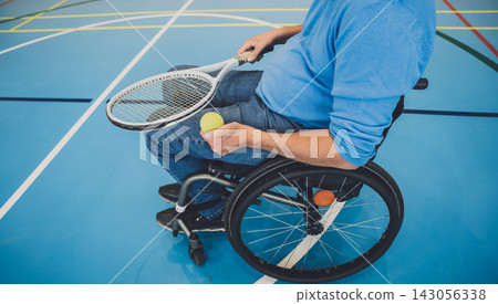 Adult man with a physical disability in a wheelchair playing tennis on indoor tennis court Adult man with a physical disability in a wheelchair playing tennis on indoor tennis court 143056338