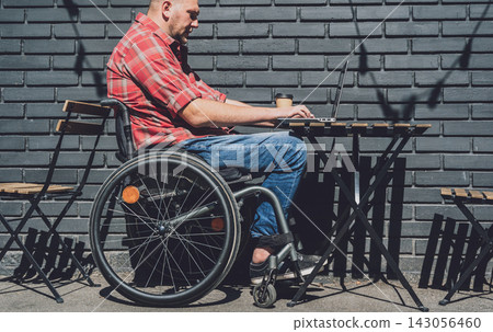 Freelancer with a physical disability in a wheelchair working at the street cafe 143056460