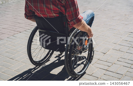 Young man with a physical disability in a wheelchair walk at the street Young man with a physical disability in a wheelchair walk at the street 143056467