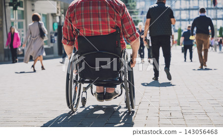 Young man with a physical disability in a wheelchair walk at the street 143056468