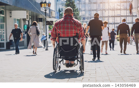 Young man with a physical disability in a wheelchair walk at the street Young man with a physical disability in a wheelchair walk at the street 143056469