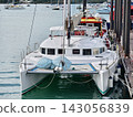 Wide marina crowded with moored sailboats and catamarans beneath partly cloudy blue sky 143056839