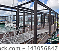 Wide marina crowded with moored sailboats and catamarans beneath partly cloudy blue sky 143056847