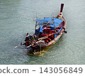 Wooden longtail fishing boat with blue canopy and exposed outboard motor 143056849