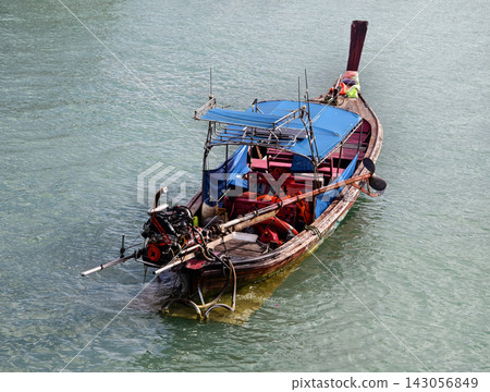 Wooden longtail fishing boat with blue canopy and exposed outboard motor Wooden longtail fishing boat with blue canopy and exposed outboard motor 143056849