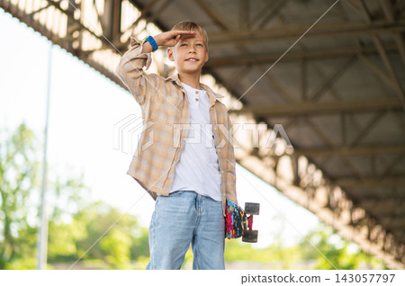 Fair-haired boy of school age with a skateboard looking confident Fair-haired boy of school age with a skateboard looking confident 143057797