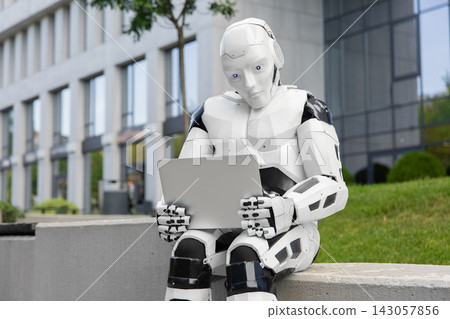 Humanoid robot holding laptop computer 143057856