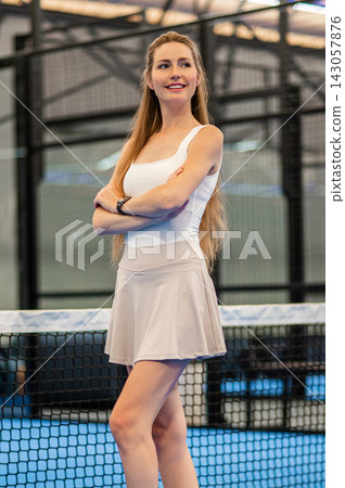 Pretty long-haired woman in a tennis skirt standing at the paddle court Pretty long-haired woman in a tennis skirt standing at the paddle court 143057876