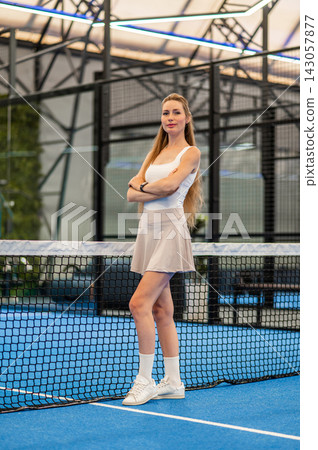 Pretty long-haired woman in a tennis skirt standing at the paddle court 143057877