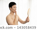 A man looks in the mirror after getting his beard removed. 143058439