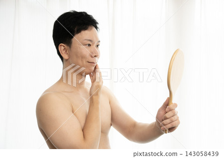 A man looks in the mirror after getting his beard removed. A man looks in the mirror after getting his beard removed. 143058439