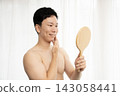A man looks in the mirror after getting his beard removed. 143058441